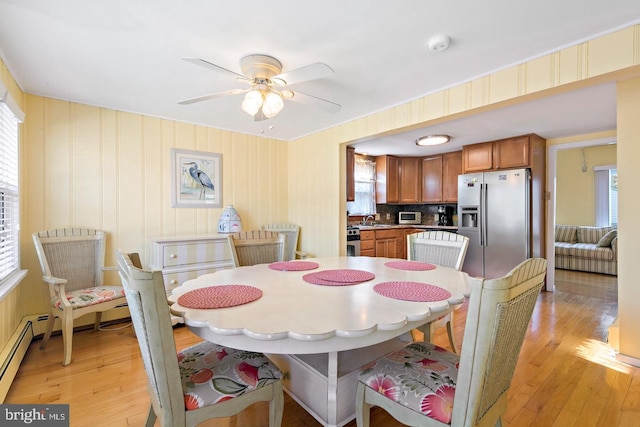 dining room with light wood-type flooring, sink, and ceiling fan