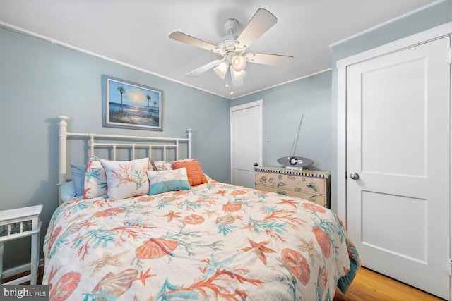 bedroom featuring ceiling fan, ornamental molding, a closet, and light hardwood / wood-style flooring