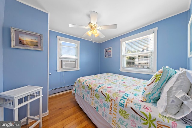 bedroom with a baseboard heating unit, multiple windows, cooling unit, and light hardwood / wood-style flooring