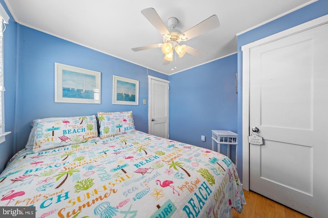 bedroom featuring light wood-type flooring, ornamental molding, and ceiling fan