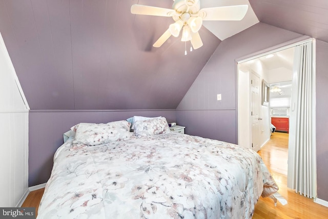 bedroom featuring light wood-type flooring, vaulted ceiling, and ceiling fan