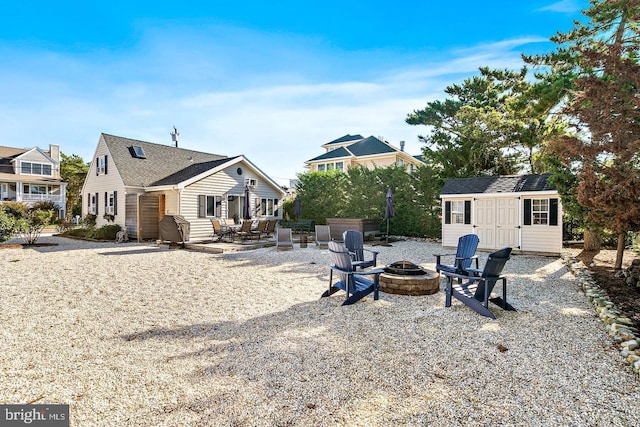 back of property with a patio, a storage shed, and a fire pit