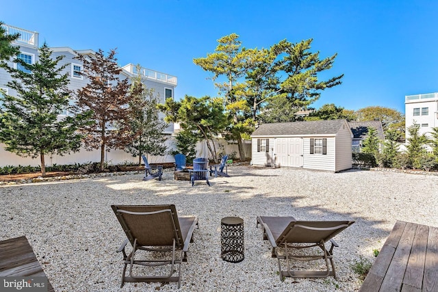 exterior space with a wooden deck, a fire pit, and an outdoor structure