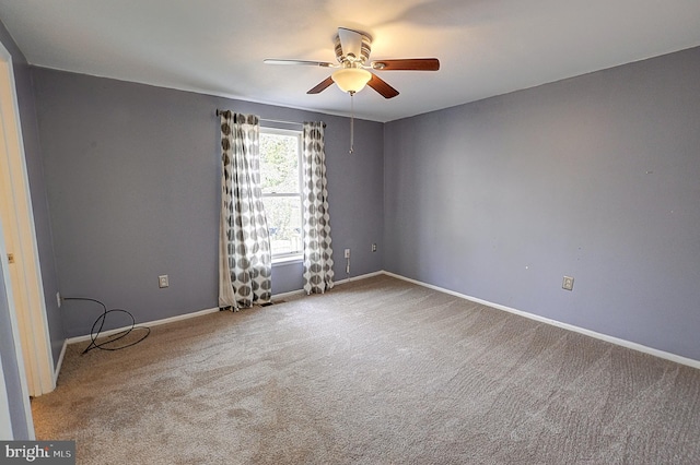 carpeted empty room with a ceiling fan and baseboards