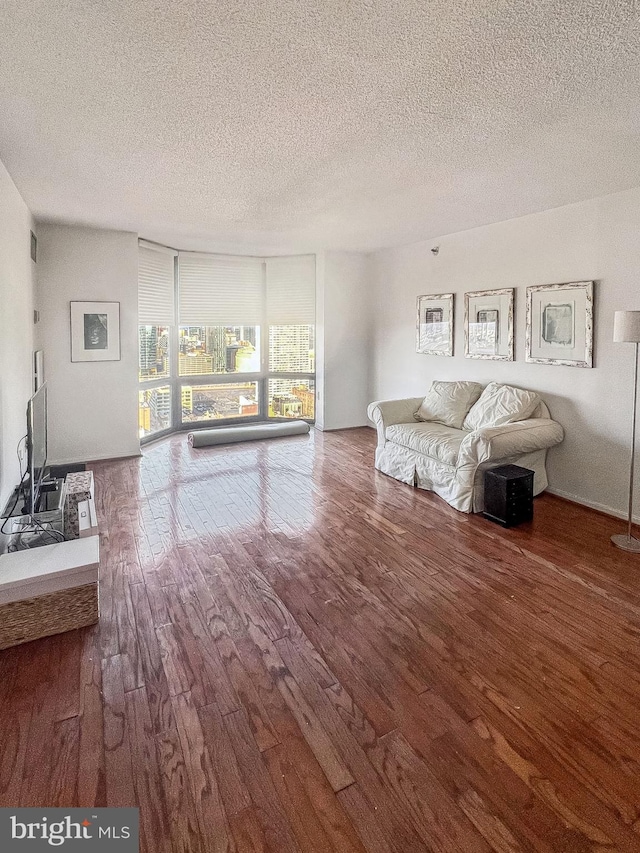 unfurnished living room with a textured ceiling and wood finished floors