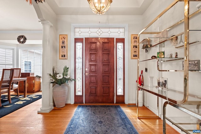 entrance foyer featuring crown molding, light hardwood / wood-style flooring, and ornate columns