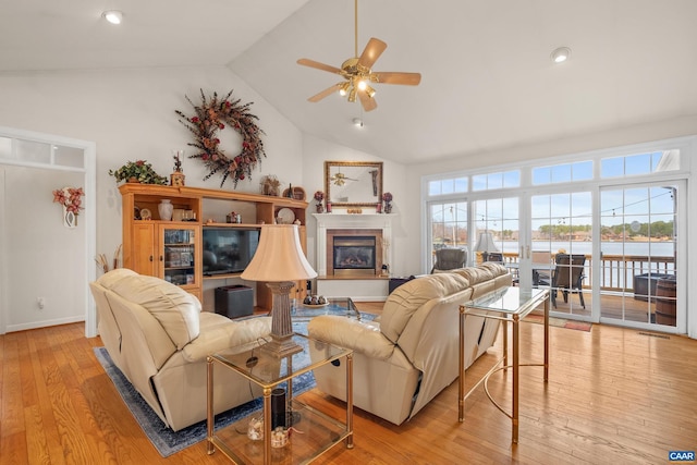 living room featuring light hardwood / wood-style floors, lofted ceiling, ceiling fan, and a fireplace