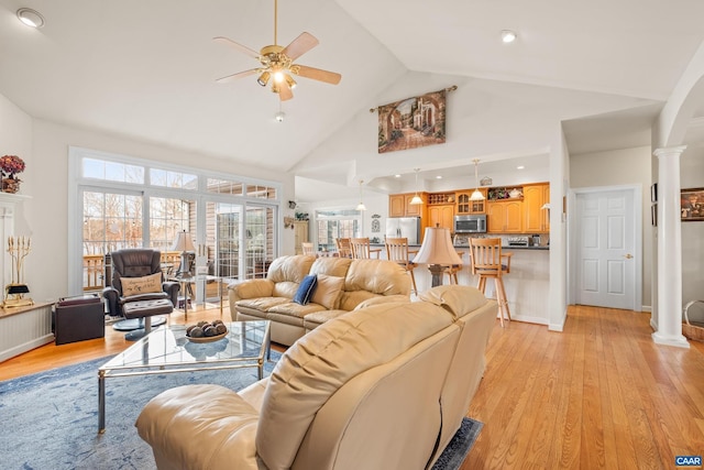 living room featuring light hardwood / wood-style floors, high vaulted ceiling, ceiling fan, and decorative columns