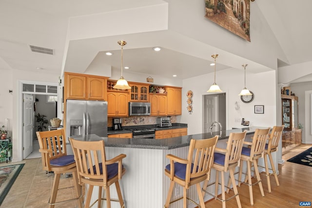 kitchen with stainless steel appliances, pendant lighting, backsplash, a kitchen bar, and kitchen peninsula