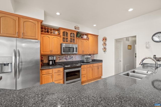 kitchen with decorative backsplash, stainless steel appliances, dark stone counters, and sink