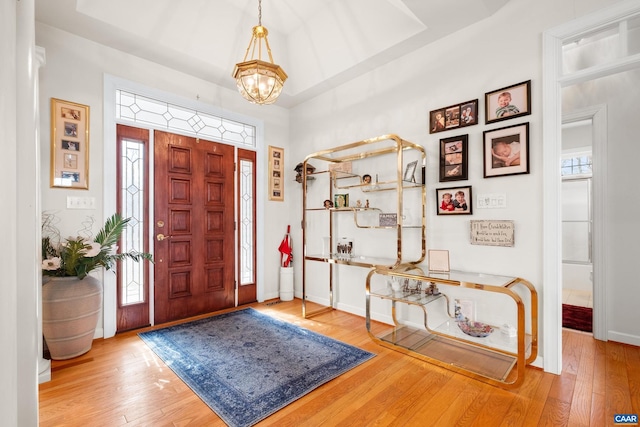 foyer entrance with a chandelier, wood-type flooring, and a healthy amount of sunlight