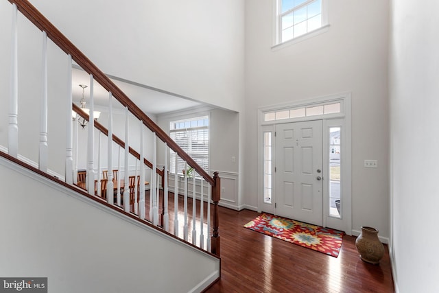 foyer entrance featuring a high ceiling, dark hardwood / wood-style floors, and a notable chandelier