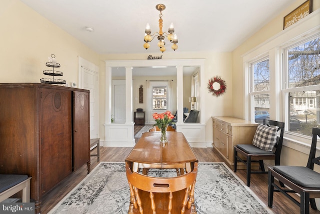 living area featuring an inviting chandelier, wood finished floors, and ornate columns