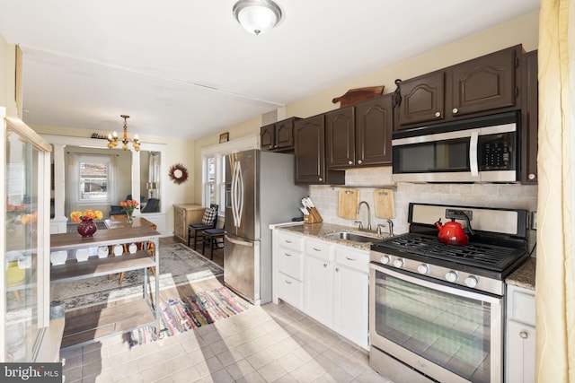 kitchen featuring a notable chandelier, stainless steel appliances, a sink, dark brown cabinets, and decorative backsplash