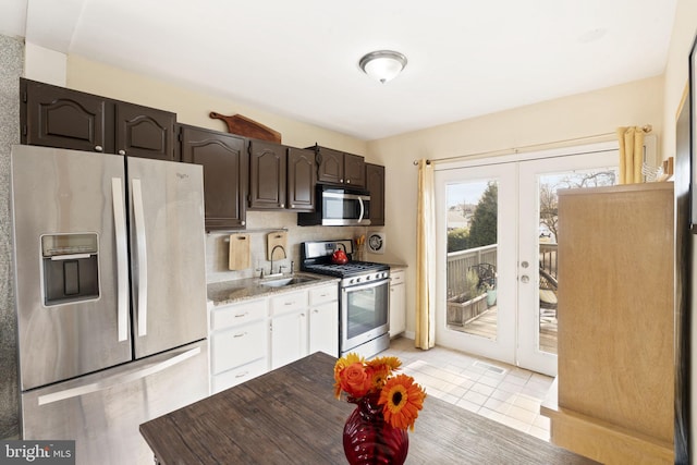 kitchen featuring stainless steel appliances, a sink, dark brown cabinets, french doors, and decorative backsplash