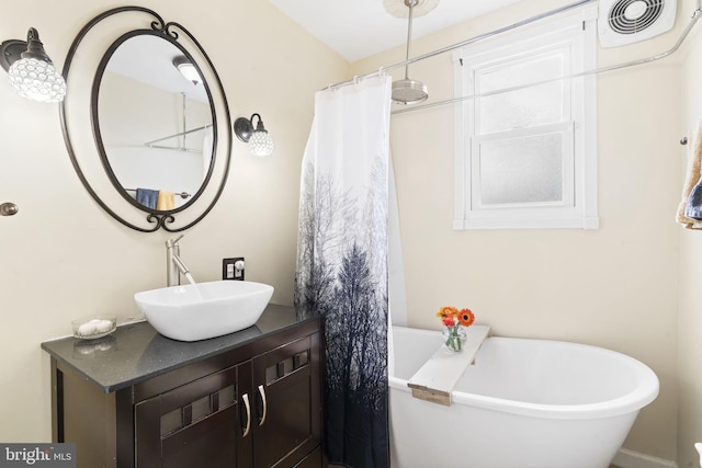 bathroom with vanity, a freestanding tub, and visible vents