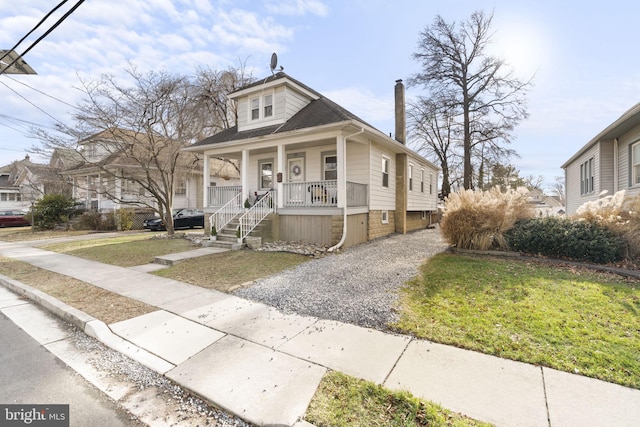 view of front of property featuring gravel driveway, a front lawn, and a porch