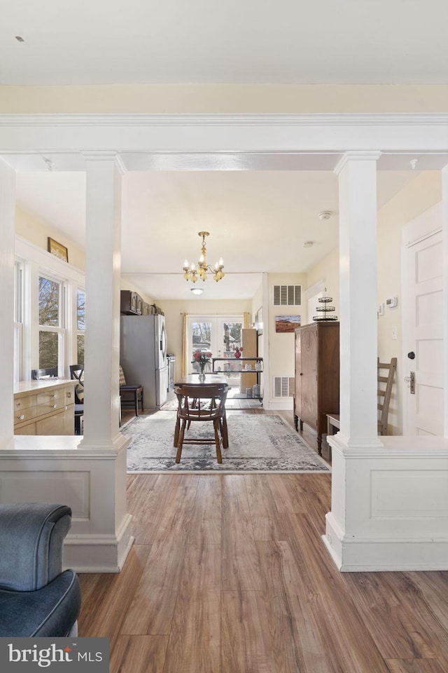 rec room with ornate columns, visible vents, wood finished floors, and an inviting chandelier