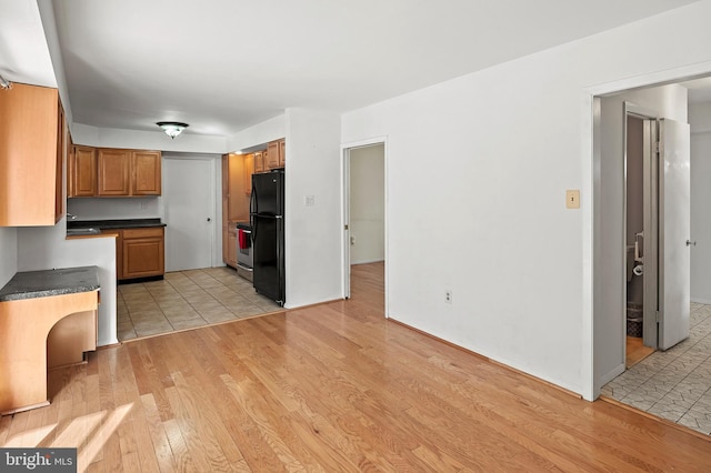 kitchen featuring sink, black refrigerator, and light hardwood / wood-style flooring