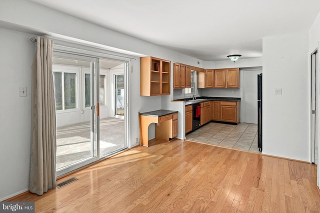 kitchen with light wood-type flooring, sink, and black dishwasher