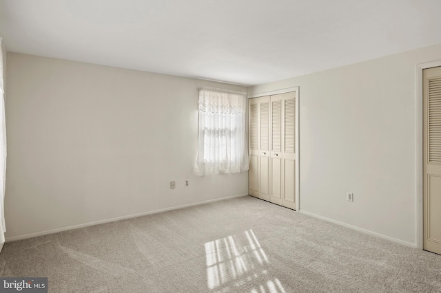 unfurnished bedroom featuring light carpet and multiple closets