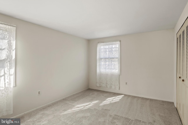 unfurnished bedroom with light carpet and a closet