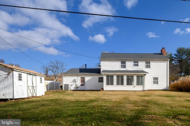 rear view of house with an outbuilding, a yard, and cooling unit