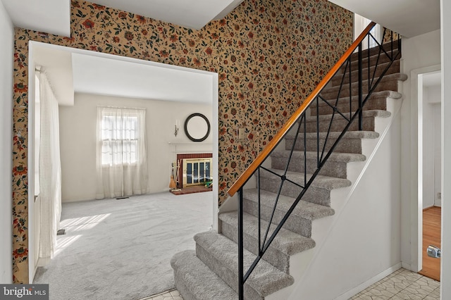 stairway featuring carpet and a fireplace