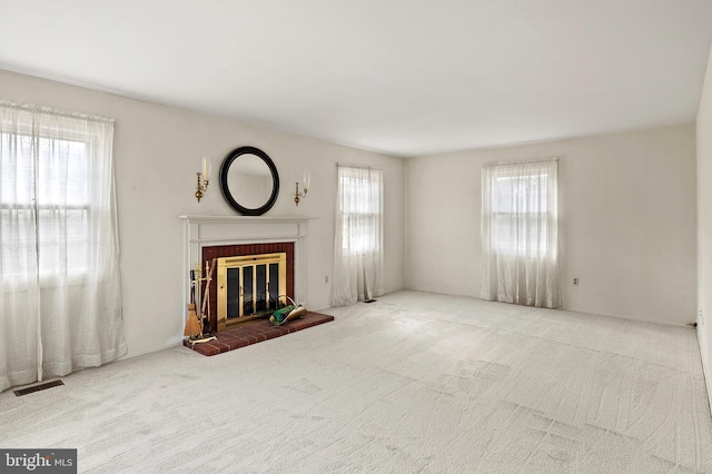 unfurnished living room with light carpet and a brick fireplace