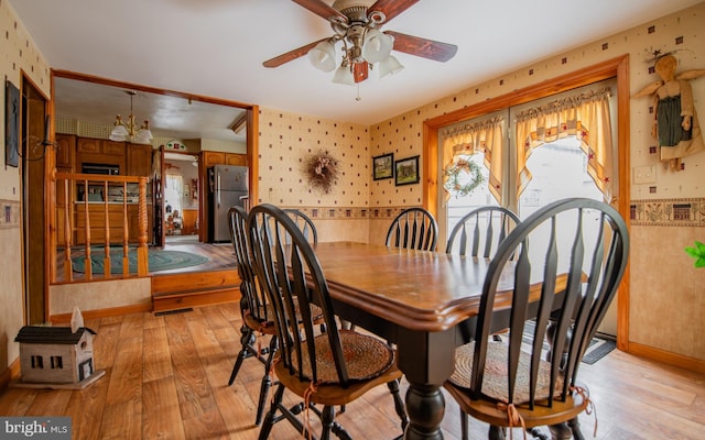 dining room with ceiling fan with notable chandelier and light hardwood / wood-style floors