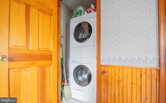 laundry room with stacked washer and clothes dryer and wooden walls