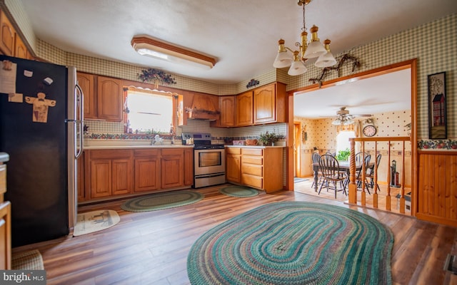 kitchen with custom exhaust hood, decorative light fixtures, light hardwood / wood-style flooring, appliances with stainless steel finishes, and ceiling fan with notable chandelier