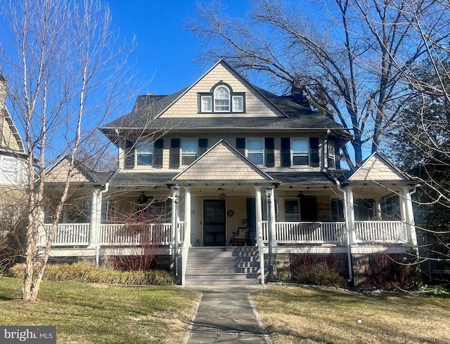 view of front of home with covered porch, a chimney, and a front yard