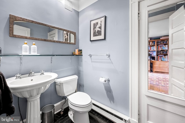 bathroom with a baseboard heating unit, baseboards, a sink, and toilet