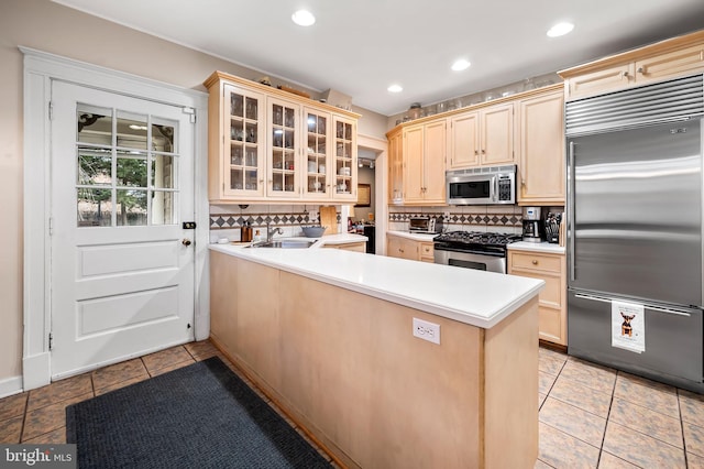 kitchen with stainless steel appliances, backsplash, a peninsula, and light tile patterned floors