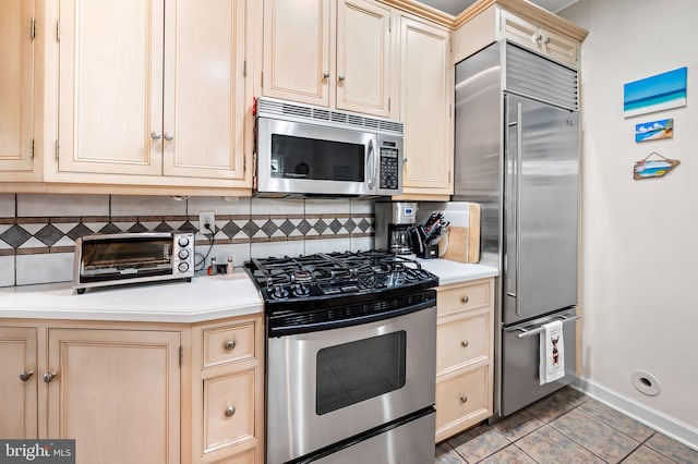 kitchen featuring cream cabinetry, stainless steel appliances, backsplash, and light countertops