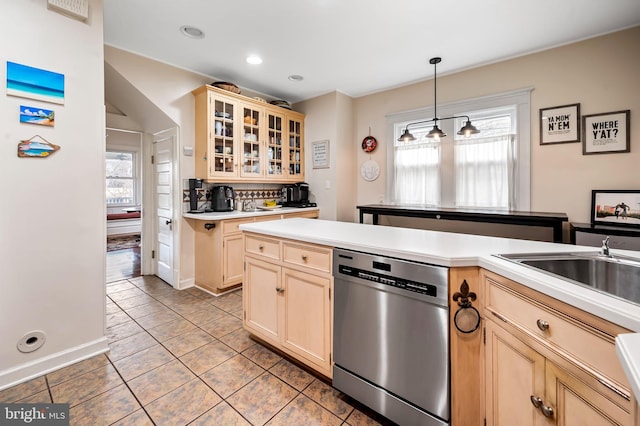 kitchen with light countertops, backsplash, stainless steel dishwasher, light brown cabinets, and a sink