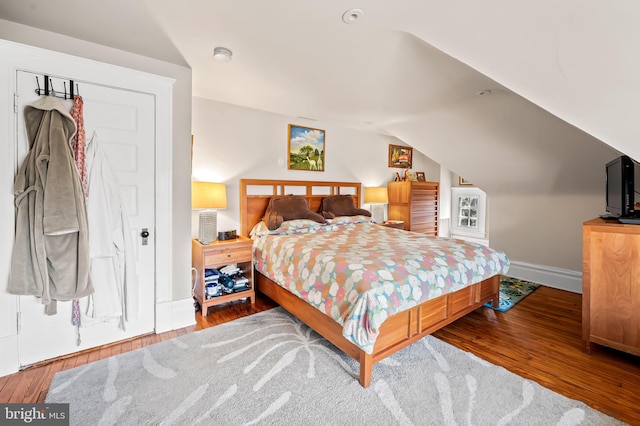 bedroom featuring lofted ceiling, hardwood / wood-style floors, and baseboards