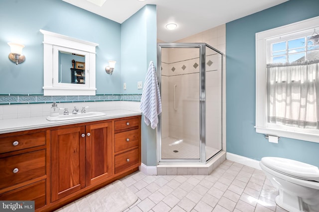 bathroom with toilet, a stall shower, vanity, tile patterned flooring, and baseboards