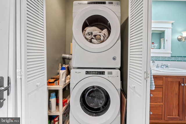 clothes washing area with laundry area, stacked washing maching and dryer, and a sink