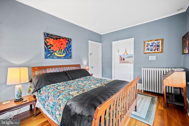 bedroom featuring crown molding, radiator heating unit, and hardwood / wood-style flooring