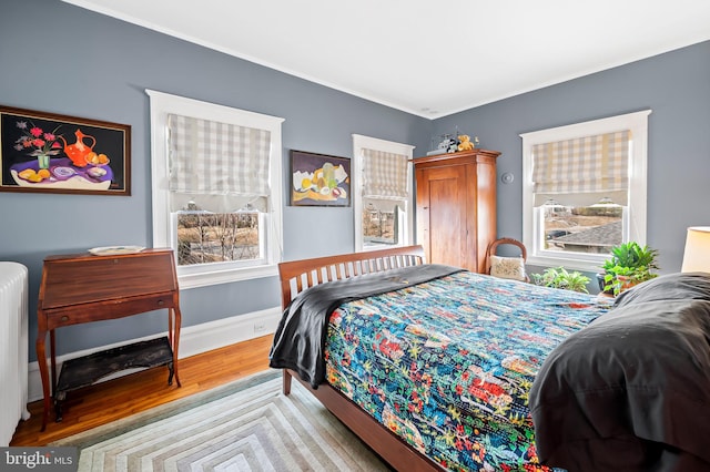 bedroom with radiator, baseboards, and wood finished floors