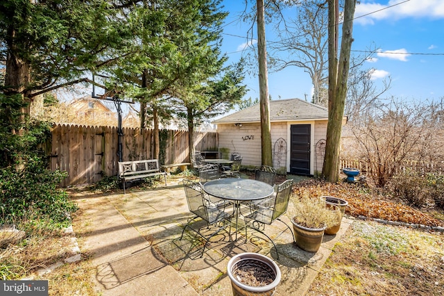 view of patio with fence, outdoor dining area, and an outbuilding