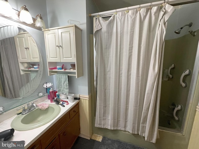 full bath with vanity, wainscoting, and a stall shower