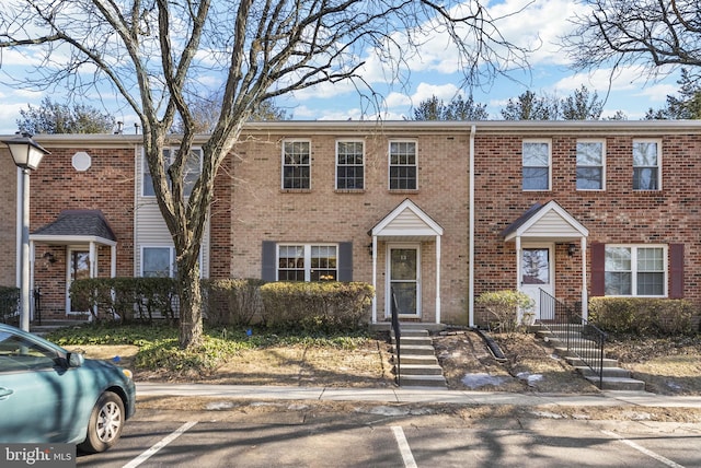 view of property featuring uncovered parking and brick siding