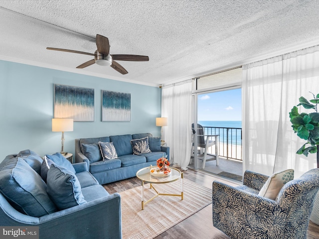 living area with a water view, crown molding, and wood finished floors