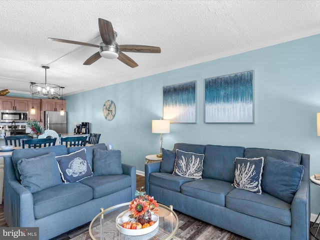 living area featuring a textured ceiling, ceiling fan with notable chandelier, baseboards, ornamental molding, and dark wood-style floors