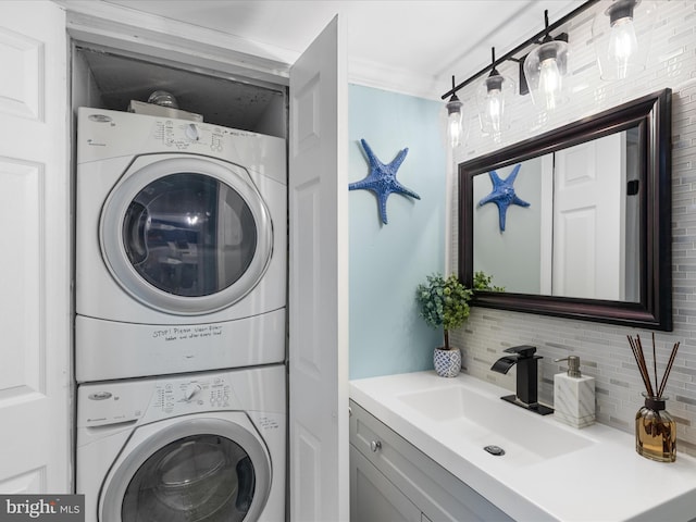 laundry area with laundry area, stacked washing maching and dryer, a sink, and crown molding