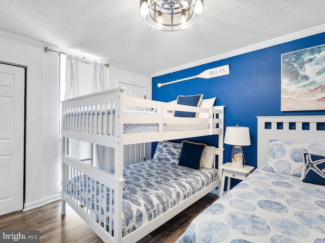 bedroom with a textured ceiling, ornamental molding, and dark wood-style flooring