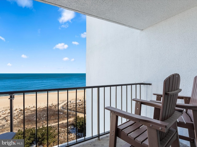 balcony with a water view and a view of the beach